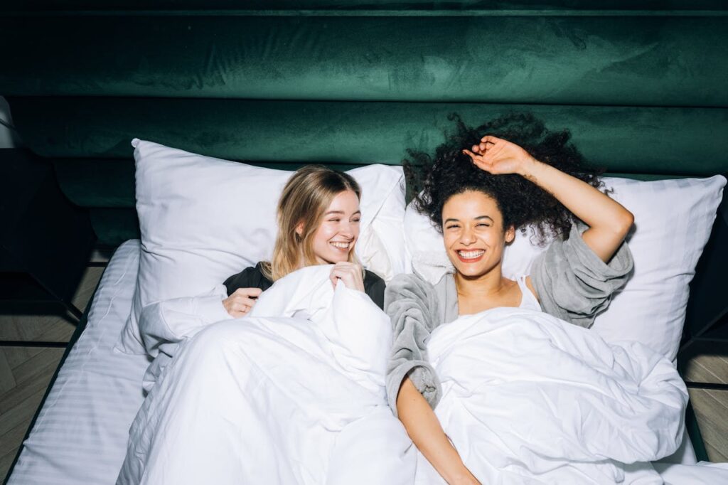 2 Frauen liegen angezogen im Bett und lächeln