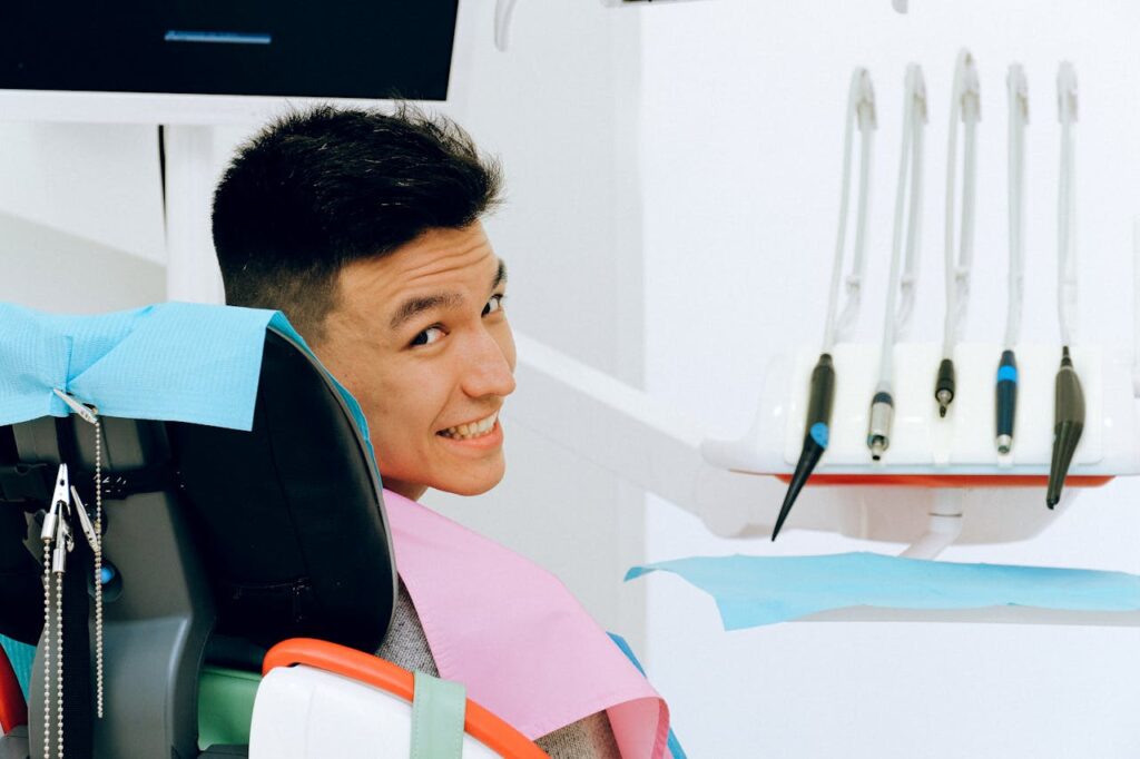 Mann sitzt auf einem Stuhl beim Zahnarzt und lächelt